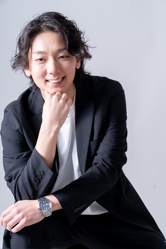 淡い背景でネイビージャケットの着座ポートレート、SNSアイコン向けの自然体プロフィール写真