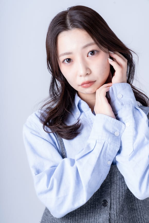 白背景で淡いブルーシャツの上半身ポートレート、SNSプロフィール用の柔らかい印象