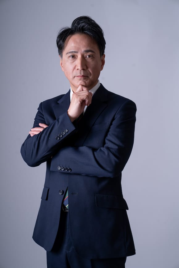 グレー背景でネイビースーツの上半身ポートレート、信頼感のあるビジネスプロフィール写真