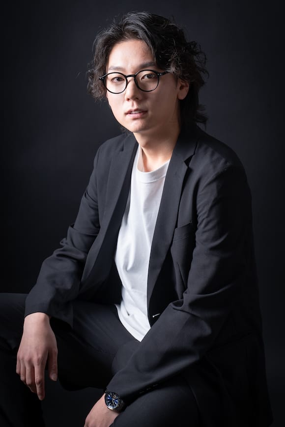 黒背景でジャケット×白Tの着座ポートレート、アーティスト向けの宣材写真